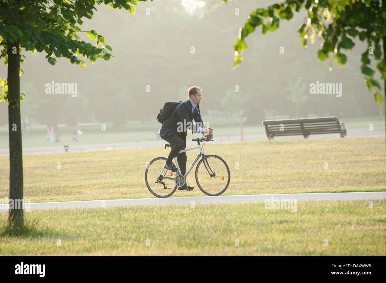 Les jeunes adultes de sexe masculin en tailleur à vélo au travail dans Kensington Gardens Park Londres en regardant son téléphone mobile riding bike Banque D'Images