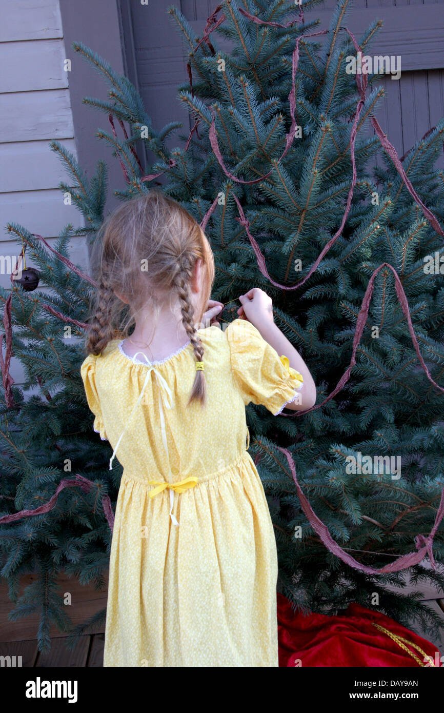 Une jeune fille mettre un ornement sur un arbre de Noël à l'extérieur Banque D'Images