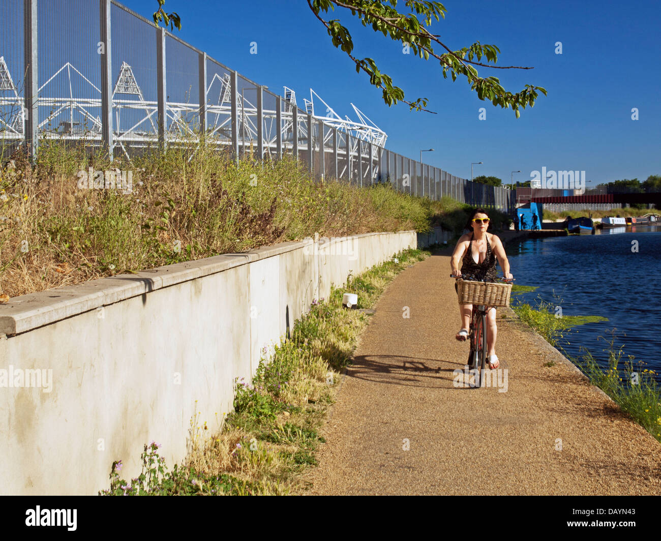 Cycliste féminin le long de la rivière Lea (Lee) Navigation à Hackney Wick montrant le stade olympique de Stratford Banque D'Images