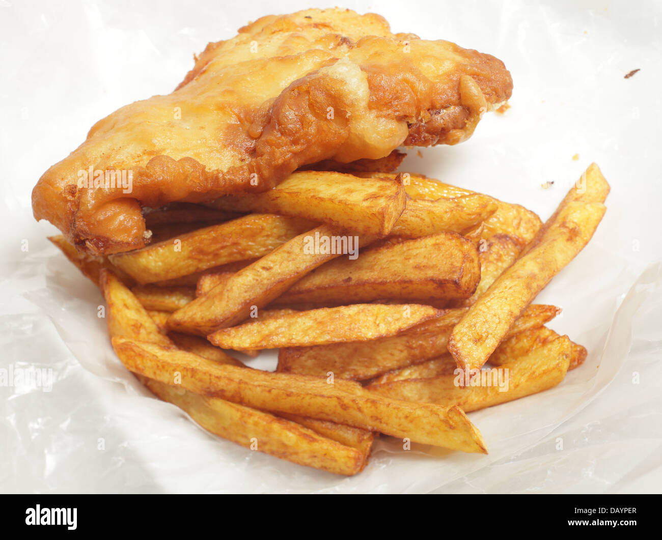 La 'chip shop' style morue frite en pâte avec chips (frites) dans un emballage de papier sulfurisé. Banque D'Images