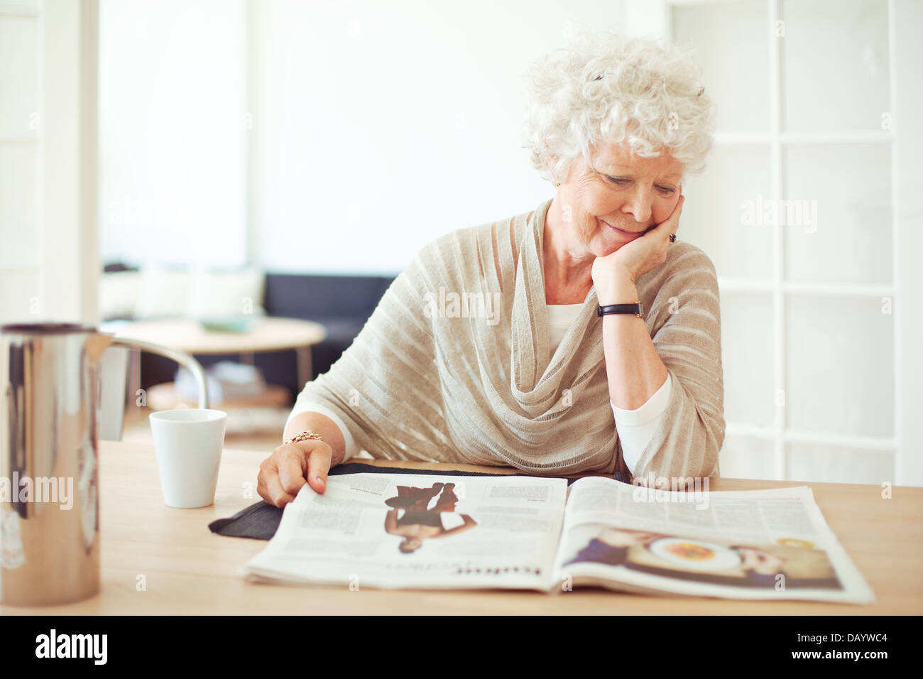 Grand-mère élégante assis à la maison la lecture d'un magazine Banque D'Images
