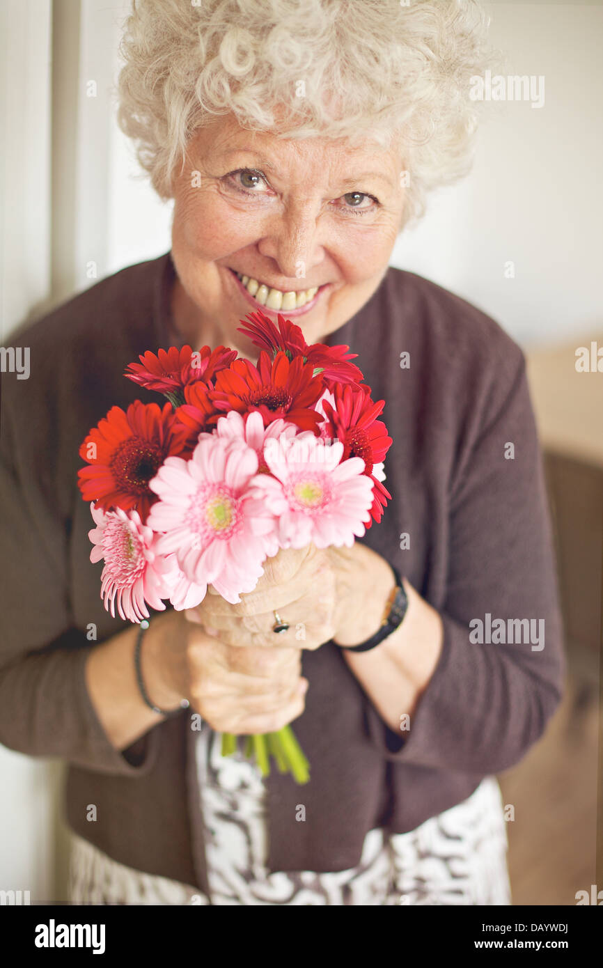 Smiling senior woman holding a bouquet of flowers Banque D'Images