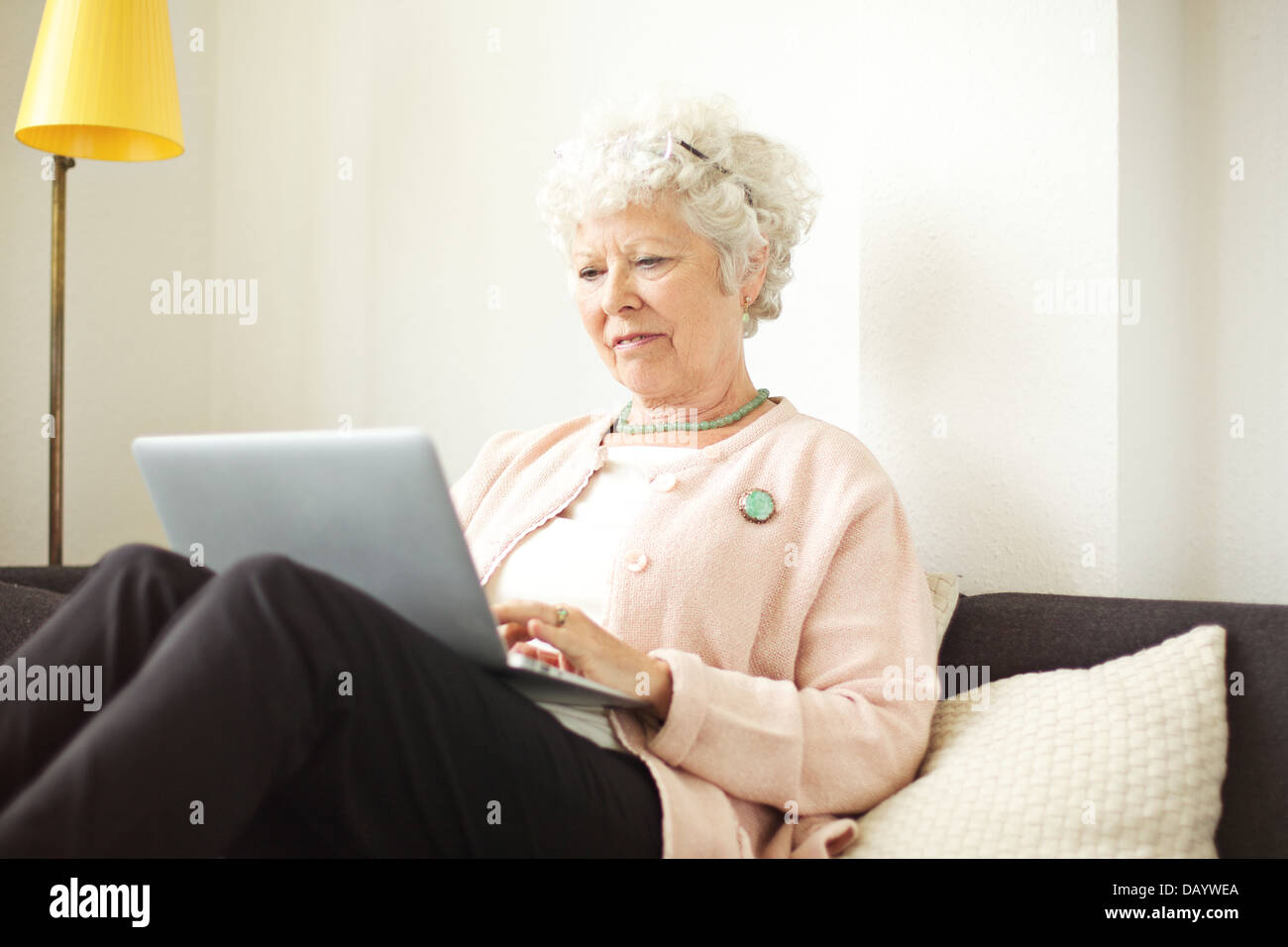 Cadre supérieur retraité femme assis à la maison en utilisant son ordinateur portable Banque D'Images
