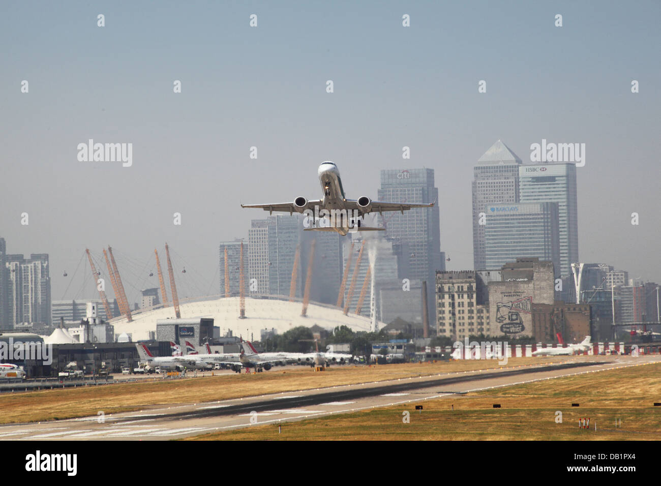 Un jet de passagers décolle de l'aéroport de London City avec Canary Wharf et le dôme du millénaire en arrière-plan Banque D'Images