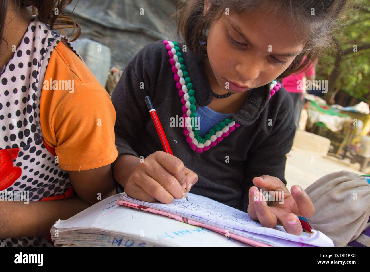 Jeune fille faire des mathématiques dans un ordinateur portable dans un bidonville de New Delhi, Inde Banque D'Images