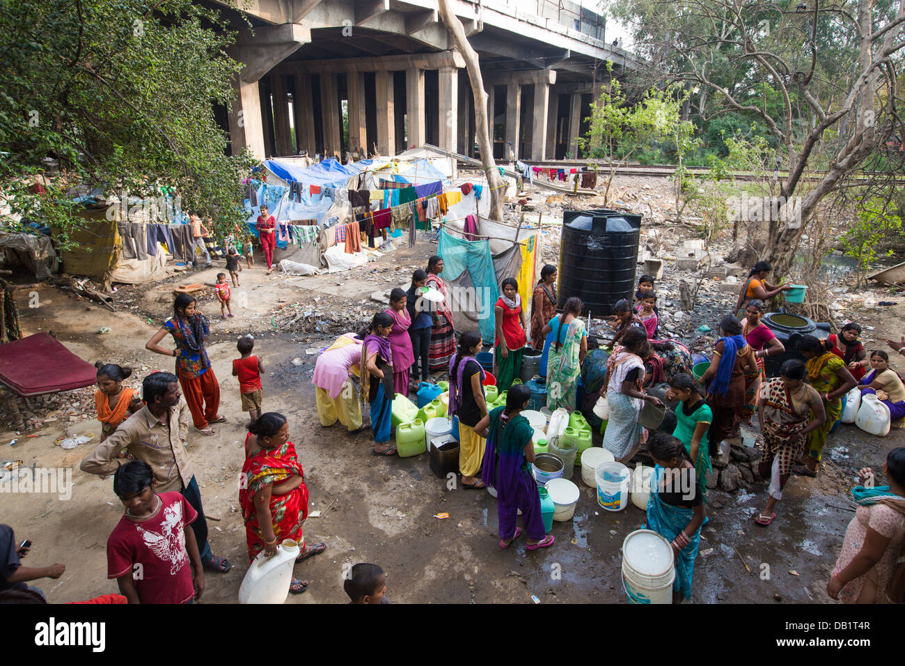 Les femmes des bidonvilles village tente de recueillir l'eau après un gouvernement distribution, New Delhi, Inde Banque D'Images