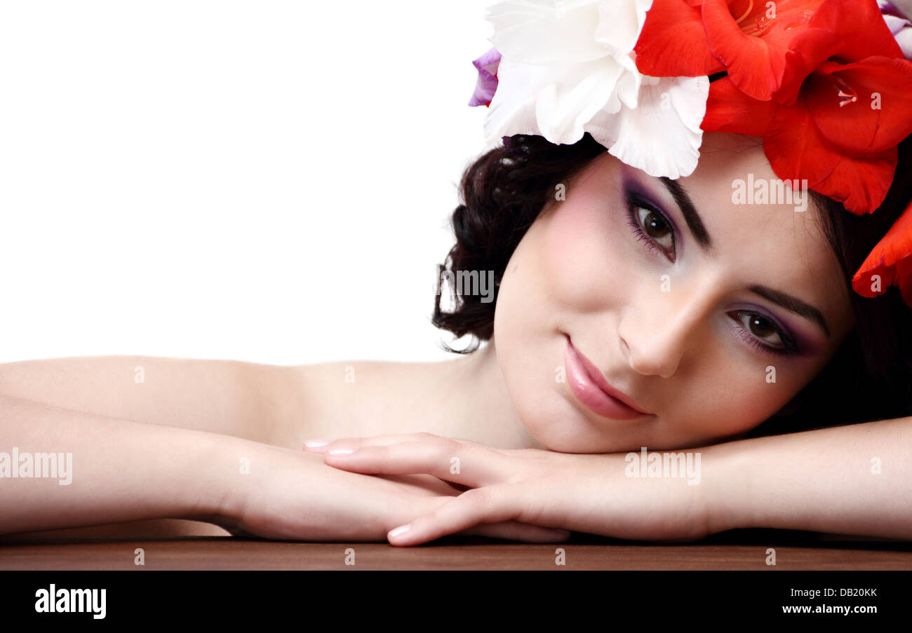 Belle jeune femme avec des fleurs dans leurs cheveux se penche sur l'appareil photo Banque D'Images