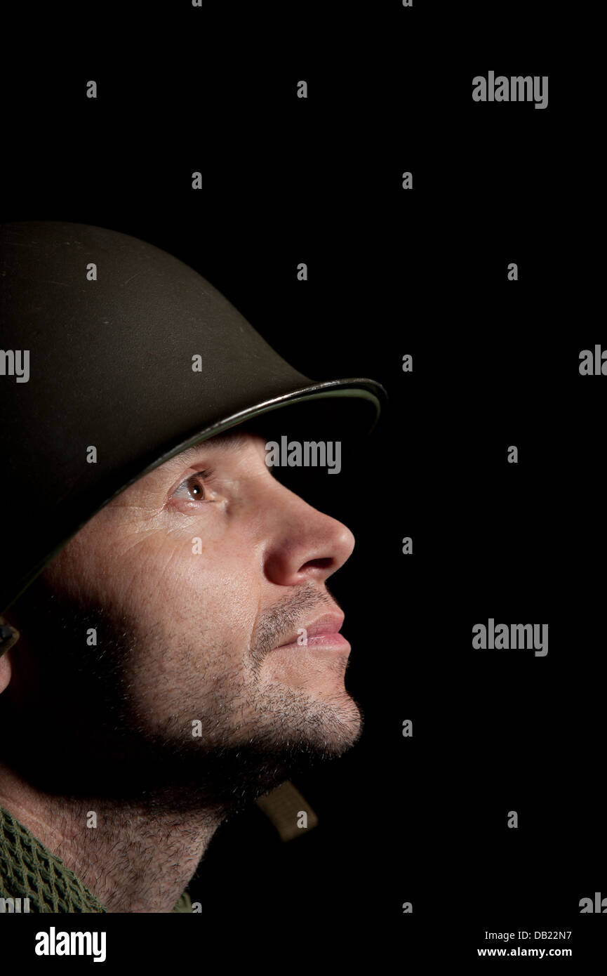 Profil Spotlit portrait d'un soldat américain WW2 vers le haut et à la recherche d'un fond noir. Banque D'Images
