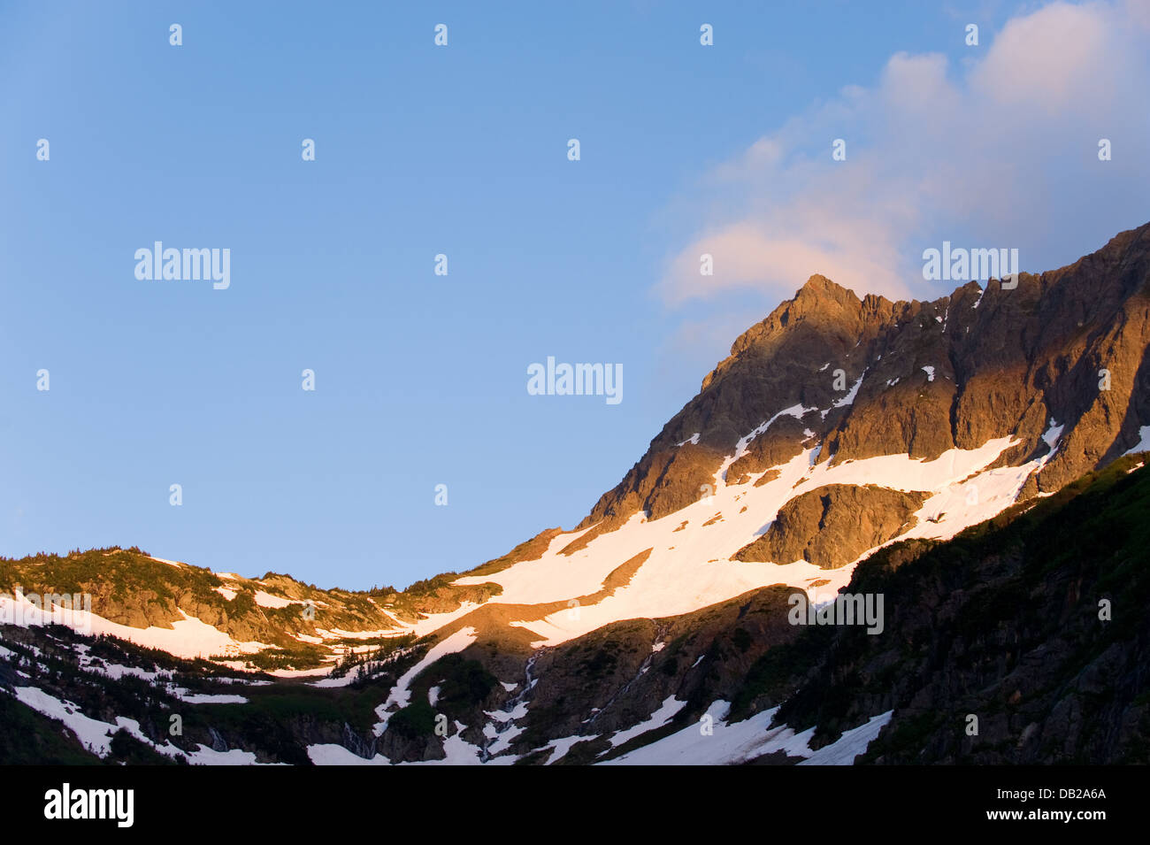 Le soleil couchant jette une lueur chaude sur les montagnes au-dessus de col Cascade à Washington's North Cascades. Banque D'Images