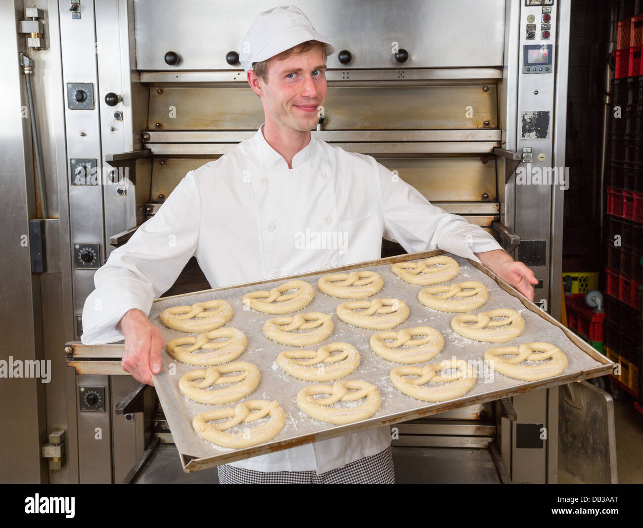 Boulangerie Baker en tenant la plaque de cuisson avec les bretzels au four Banque D'Images