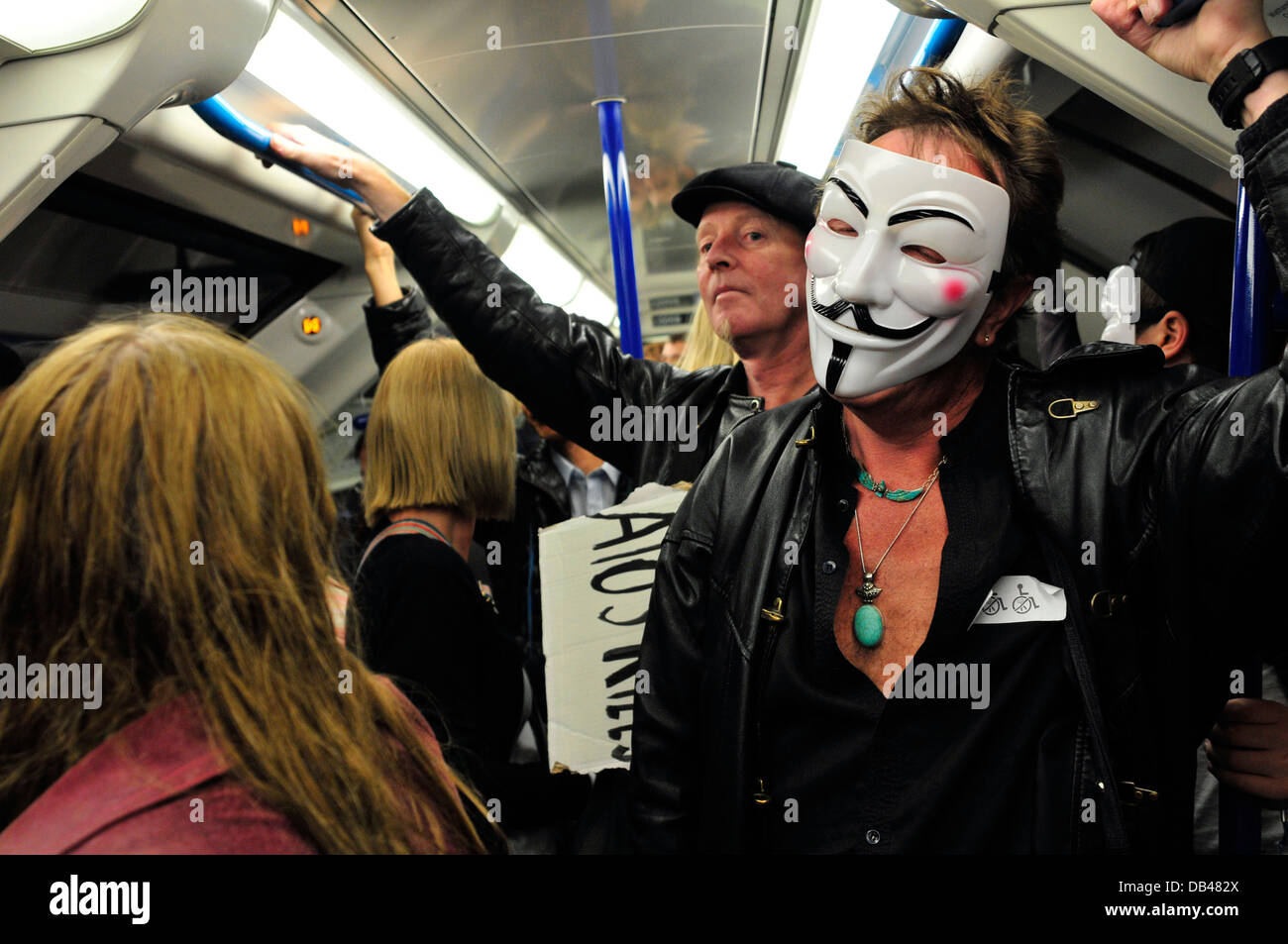Un homme portant un masque anonyme voyages dans le métro, London, UK Banque D'Images