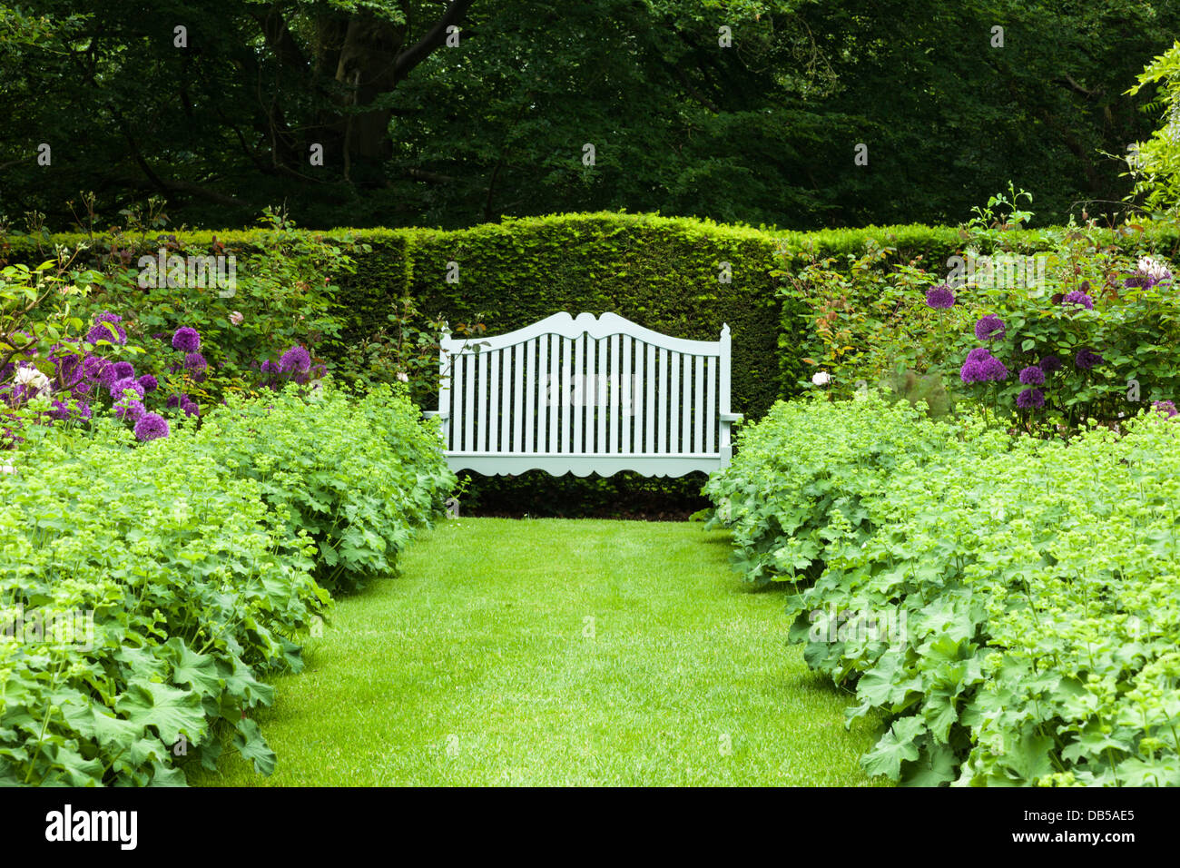 Un siège de jardin élégant flanqué de frontières floral dans le jardin du philosophe de Cottesbrooke Hall, le Northamptonshire, Angleterre Banque D'Images