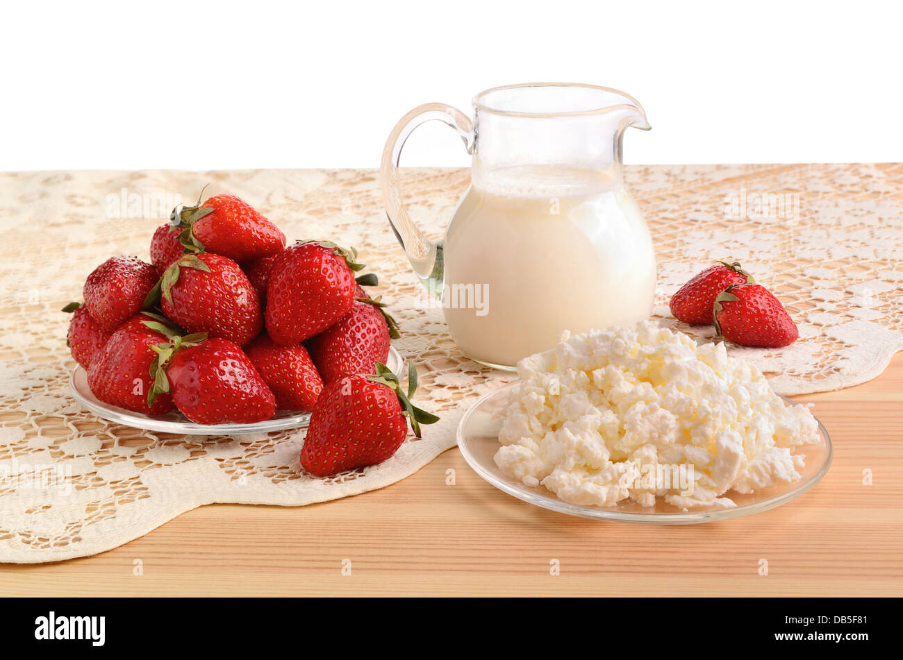 Une fraise mûre, du lait et du fromage cottage sur une nappe en bonneterie Banque D'Images