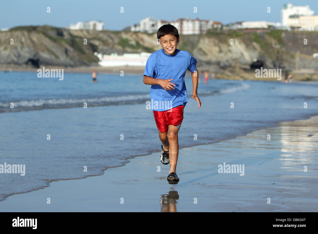 Jeune garçon joue et s'exécute dans le surf le long d'une plage anglaise près de Sunset Banque D'Images