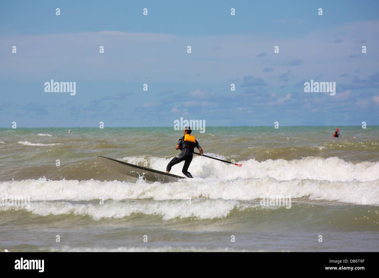 Chicago, Illinois, USA. 24 août, 2013. Un homme debout sur un paddle board  surfe sur une vague à la plage de Montrose. Un vent du nord soufflant  pendant deux jours a été