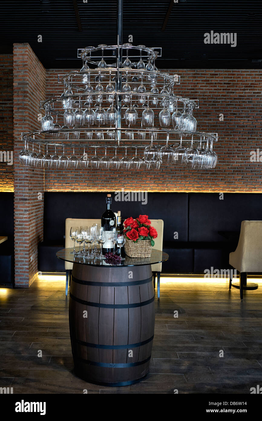 Bar à vins exposition publicitaire intérieure avec verres à vin suspendus, tonneau à vin, bouteilles de vins et panier en osier de roses rouges Banque D'Images