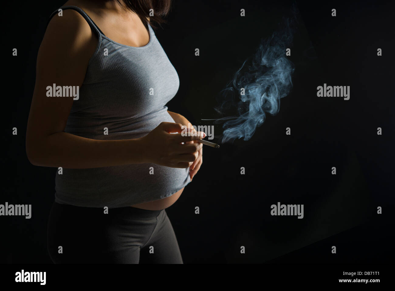 Fumeur mère enceinte sur un plus de lumière sombre dramatique Banque D'Images