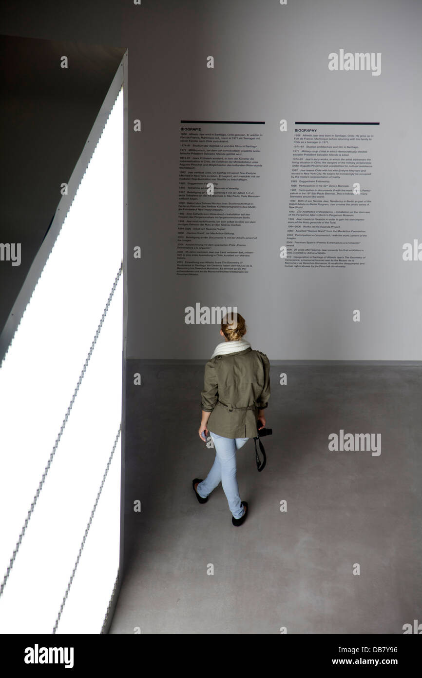 Une jeune femme lit l'information sur le mur d'une galerie d'art Banque D'Images