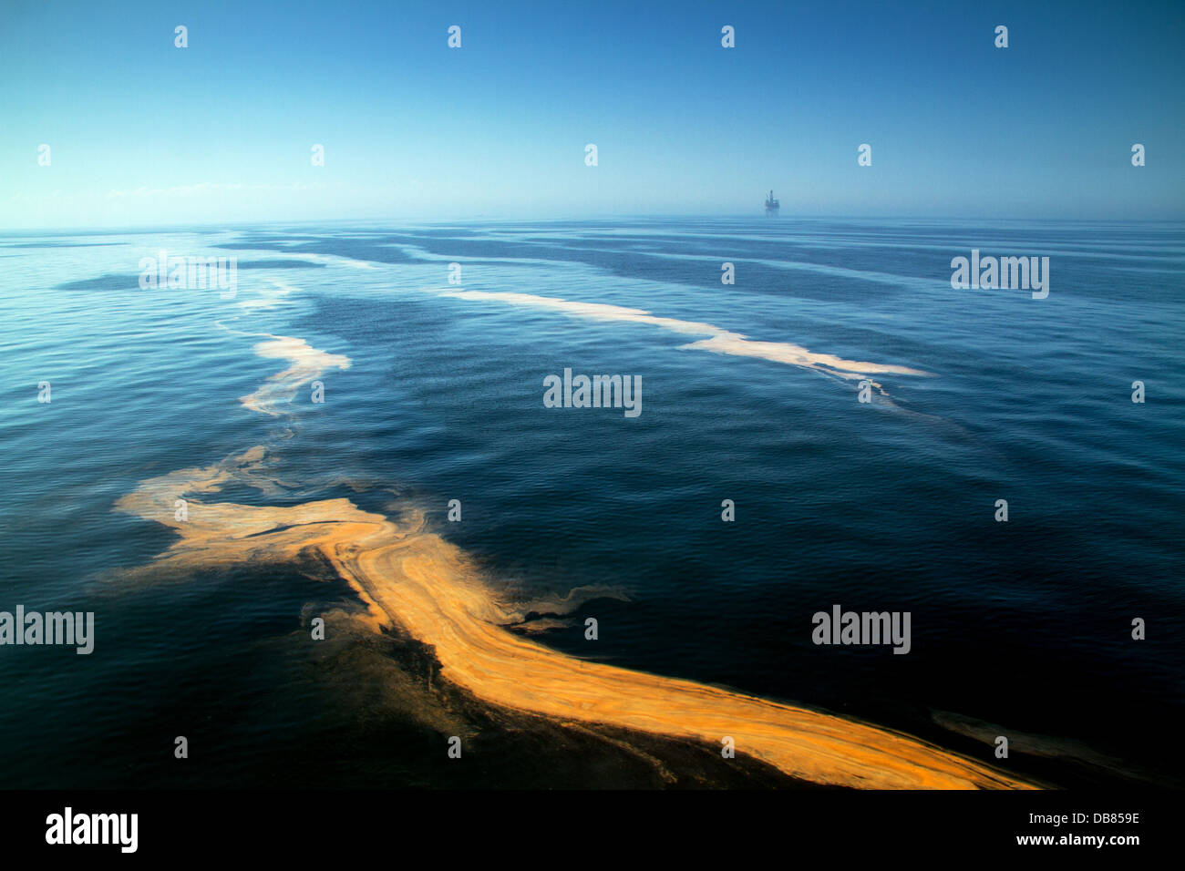 La pollution de l'eau dans la mer d'Irlande avec une écume sur la surface contre un ciel bleu avec une plate-forme pétrolière dans la distance Banque D'Images