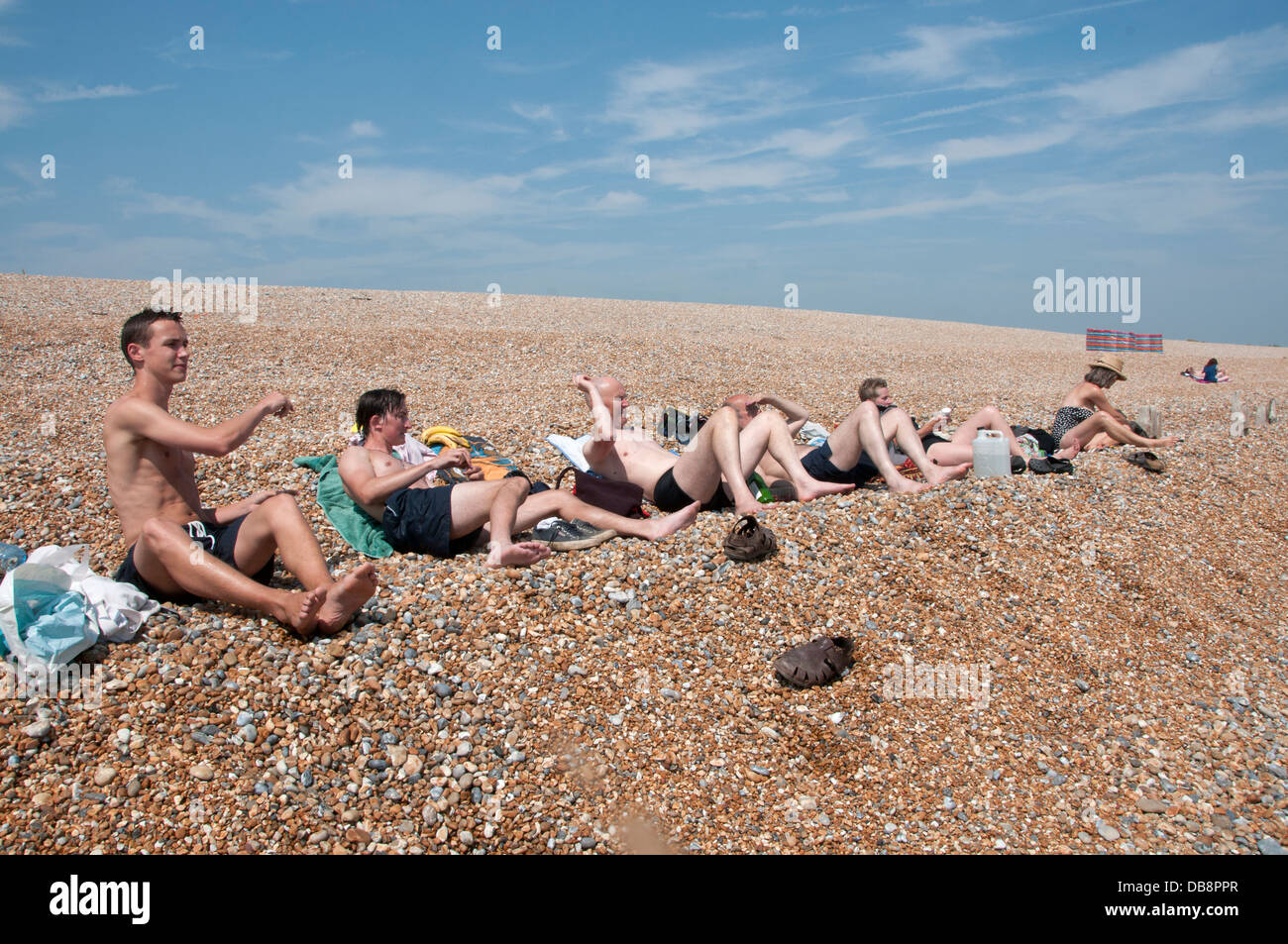 Pett Level Plage. East Sussex. Les hommes de jeter des pierres en direction de la mer. Banque D'Images