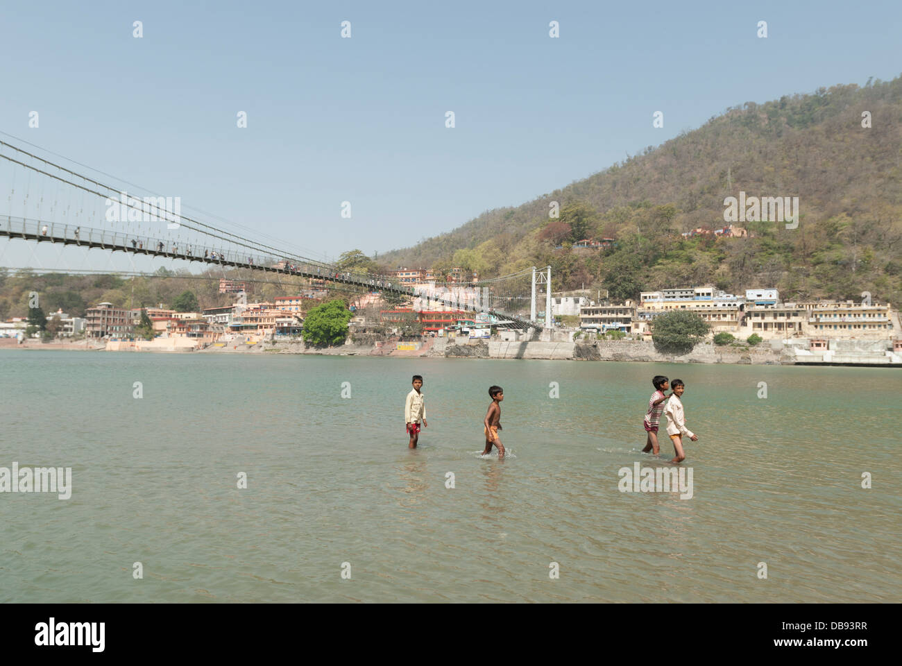 Rishikesh, Inde. Les garçons indiens jouent dans le Gange, Rishikesh, Uttarakhand, Inde, avec le pont suspendu de Lakshman Jhula en arrière-plan Banque D'Images