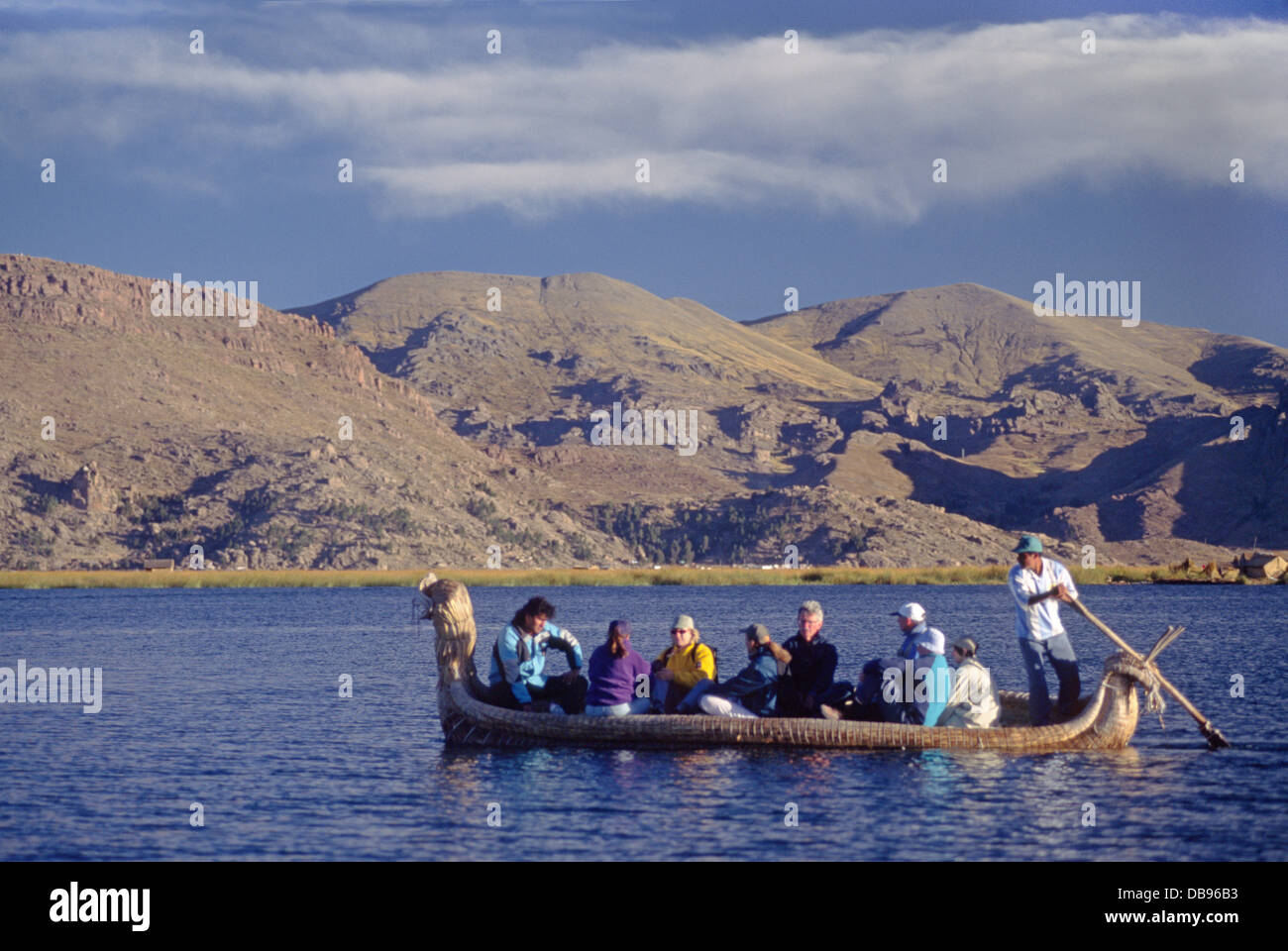Un homme Aymara nous pilotes d'une île flottante à l'autre par Reed Yacht - Lac Titicaca - Pérou Banque D'Images