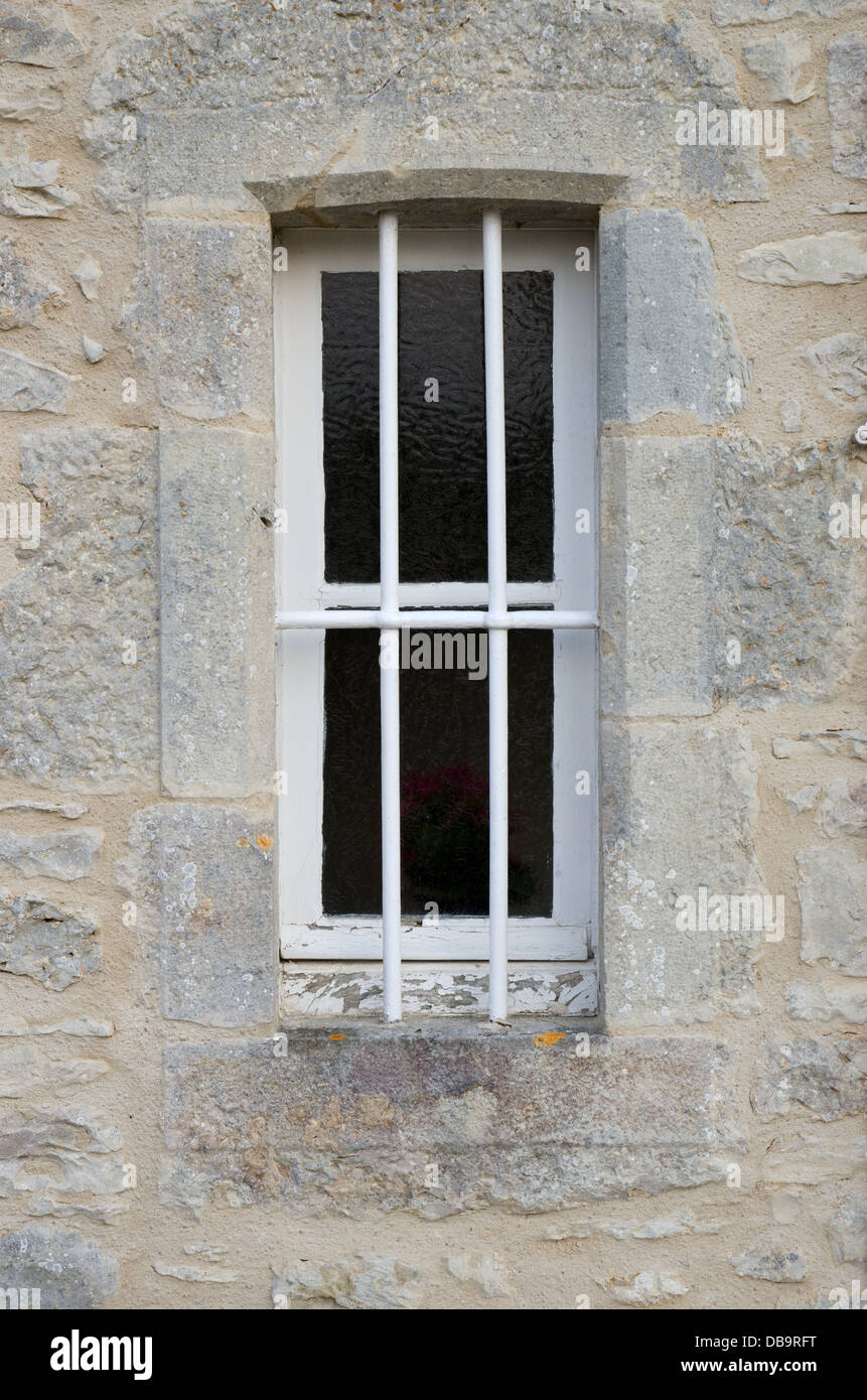 Une petite fenêtre avec des bars situé dans un mur de pierre Banque D'Images