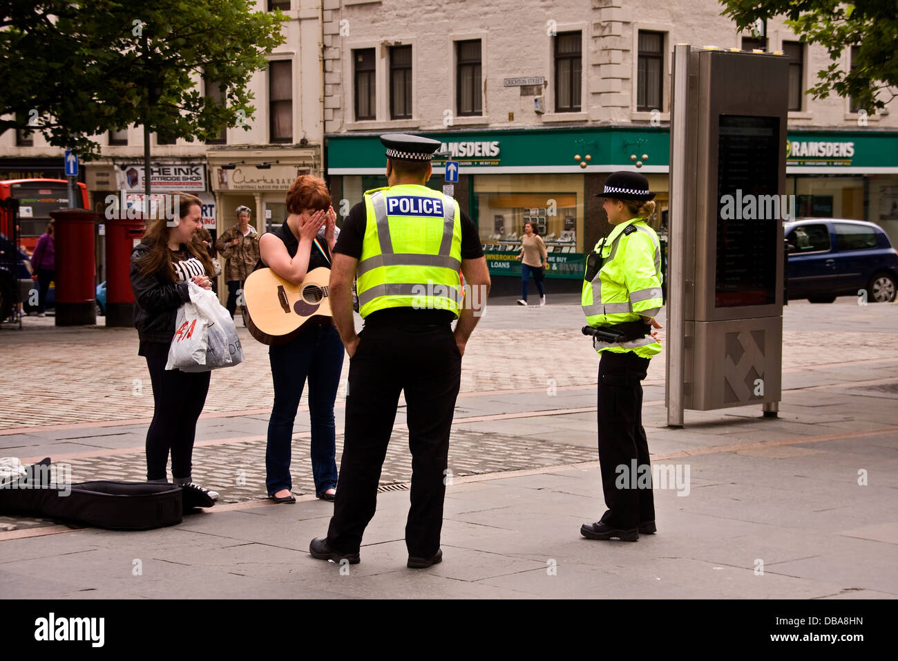 Deux agents de police sur le chat et d'avoir du plaisir avec une femme dans le centre-ville de Dundee Busker,UK Banque D'Images