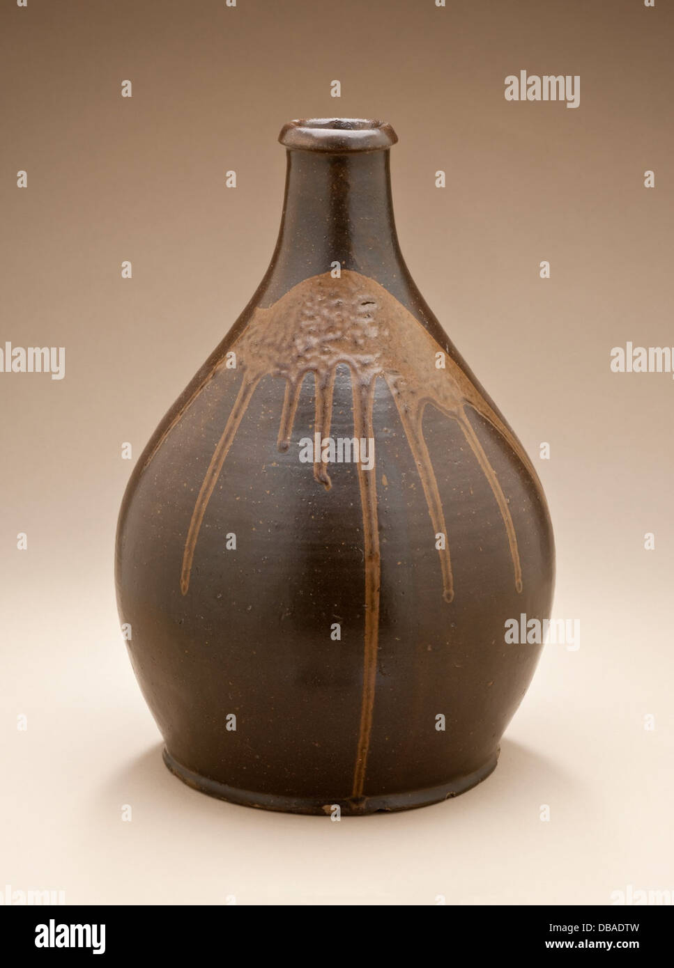 Cette bouteille de saké japonais traditionnel (tokkuri) est fabriquée en céramique, conçue pour stocker et verser du saké, un vin de riz. La bouteille présente un design simple mais élégant avec un corps arrondi et un col étroit, représentatif de l'art de la poterie japonaise. Banque D'Images