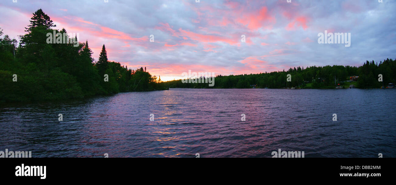 Panorama de soleil rose sur un lac du nord avec des chalets à terre Banque D'Images