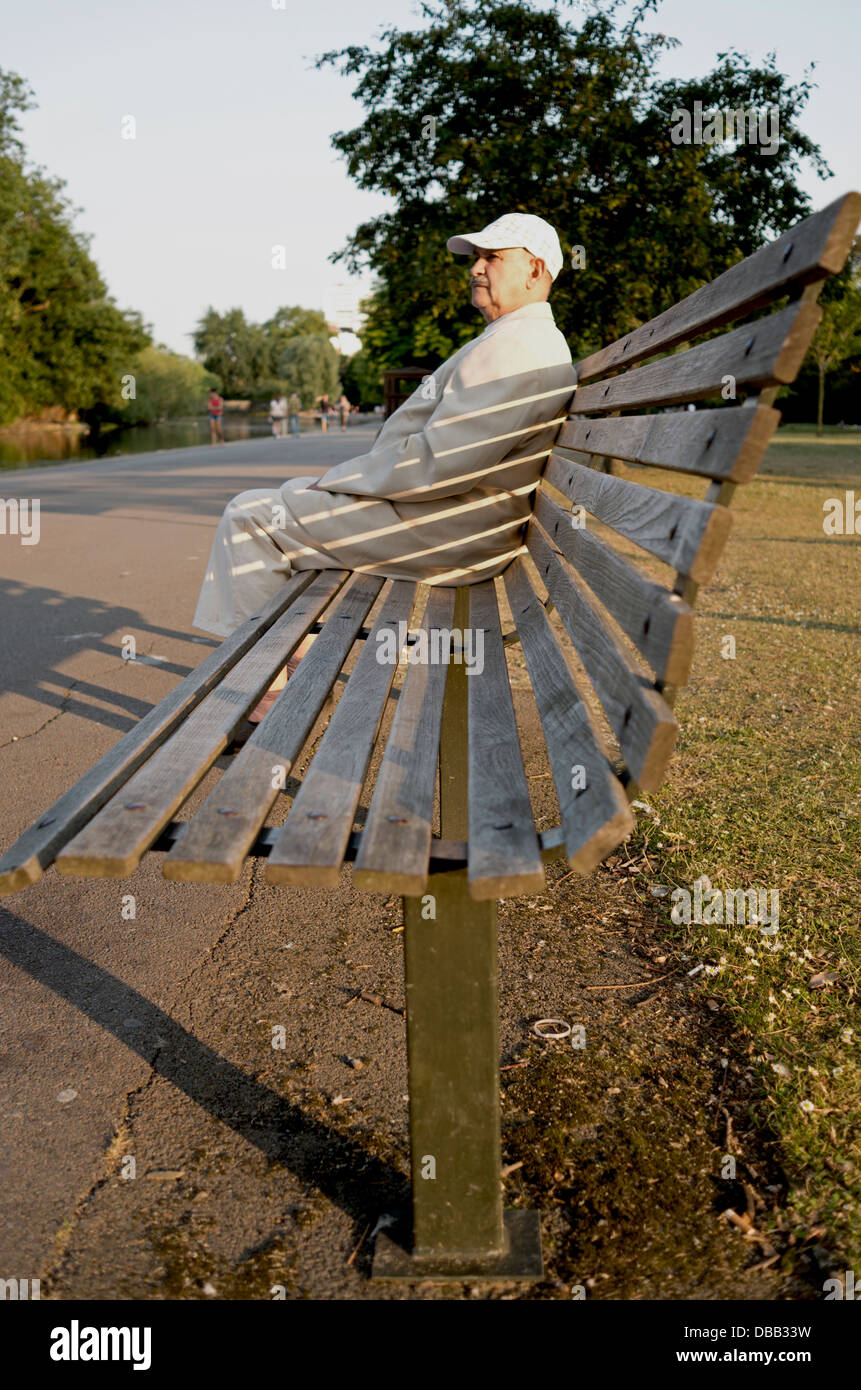 Homme assis dans le soleil de fin d'après-midi sur un banc de Regent's Park, Londres. Portrait. Banque D'Images