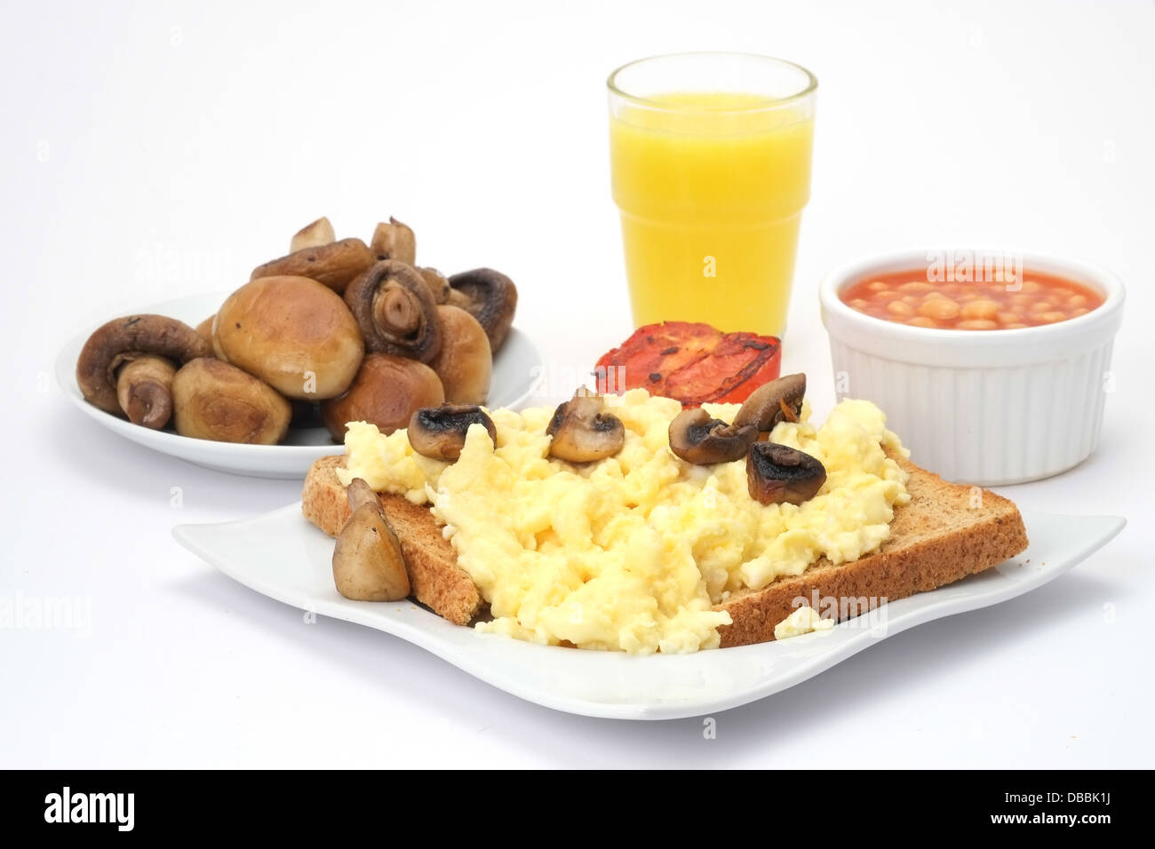 Des œufs brouillés sur du pain grillé avec des haricots blancs, les champignons et le jus d'orange Banque D'Images