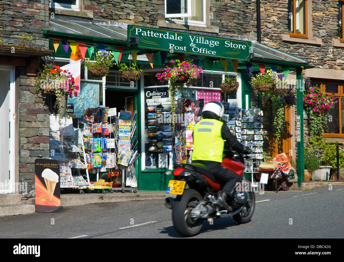 Moto passant le village store and post office, Glenridding village, Parc National de Lake District, Cumbria, Angleterre, Royaume-Uni Banque D'Images