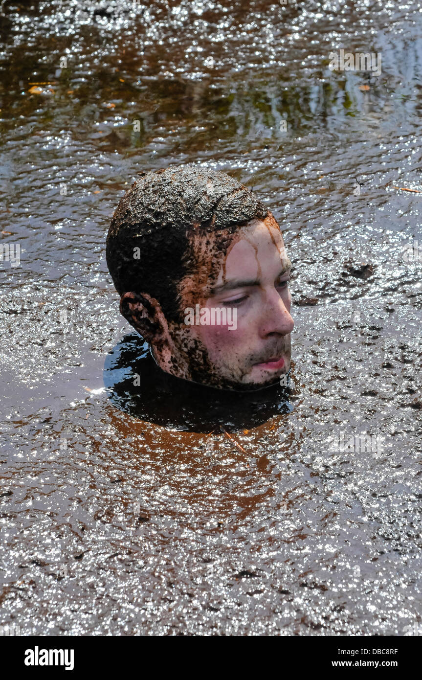 Dungannon, Irlande du Nord, 28 juillet 2013 - Un homme se trouve immergé dans la boue avec seulement sa tête montrant Crédit : Stephen Barnes/Alamy Live News Banque D'Images