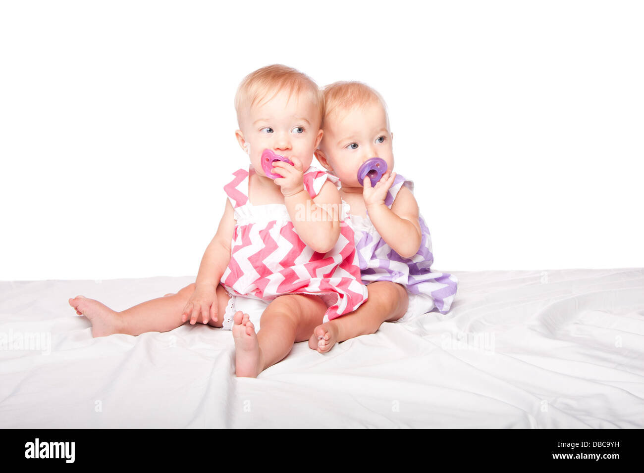 Deux Adorables Jumelles Identiques Mignon Assis Ensemble Avec Les Sucettes Sur Blanc Photo Stock Alamy