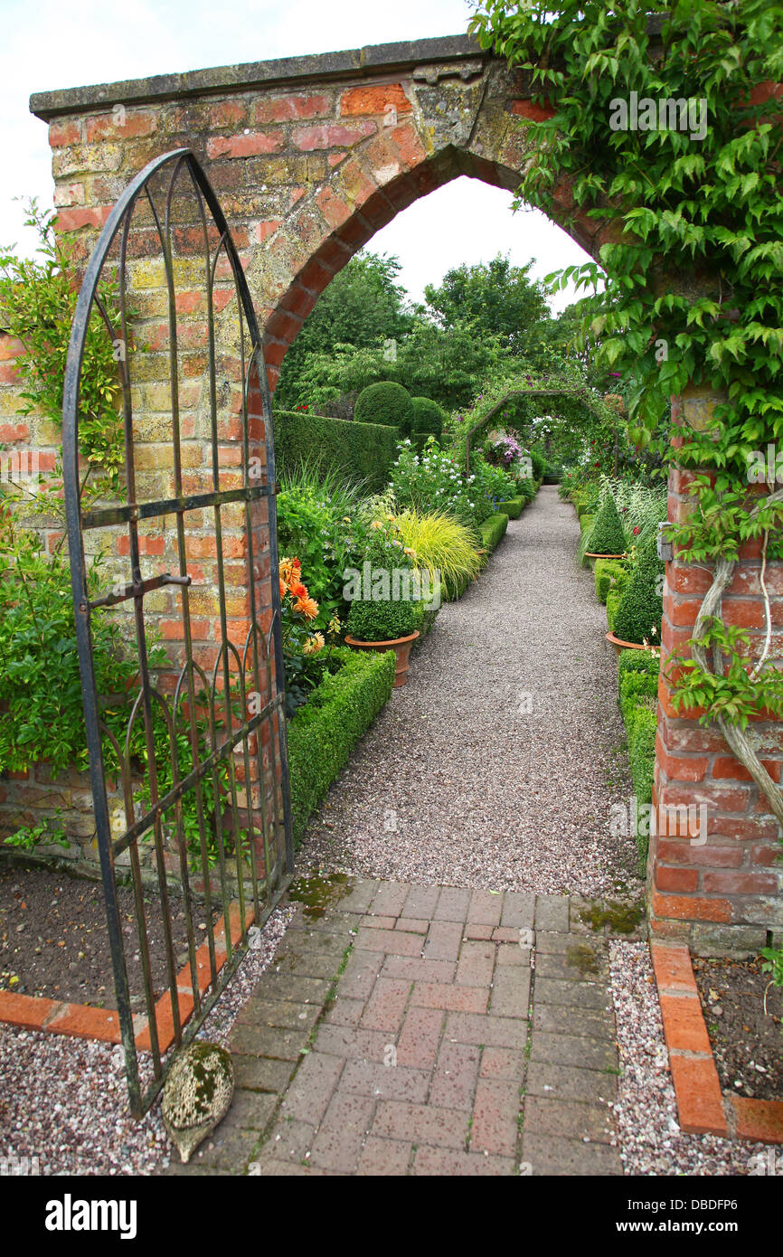 Une ancienne porte du métal dans un mur de brique à Wollerton Old Hall Gardens jardin Wollerton London Greater London England UK Banque D'Images