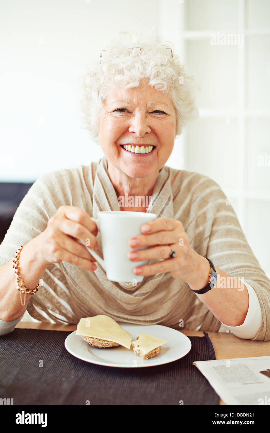 Smiling old lady avoir son petit déjeuner à la maison Banque D'Images