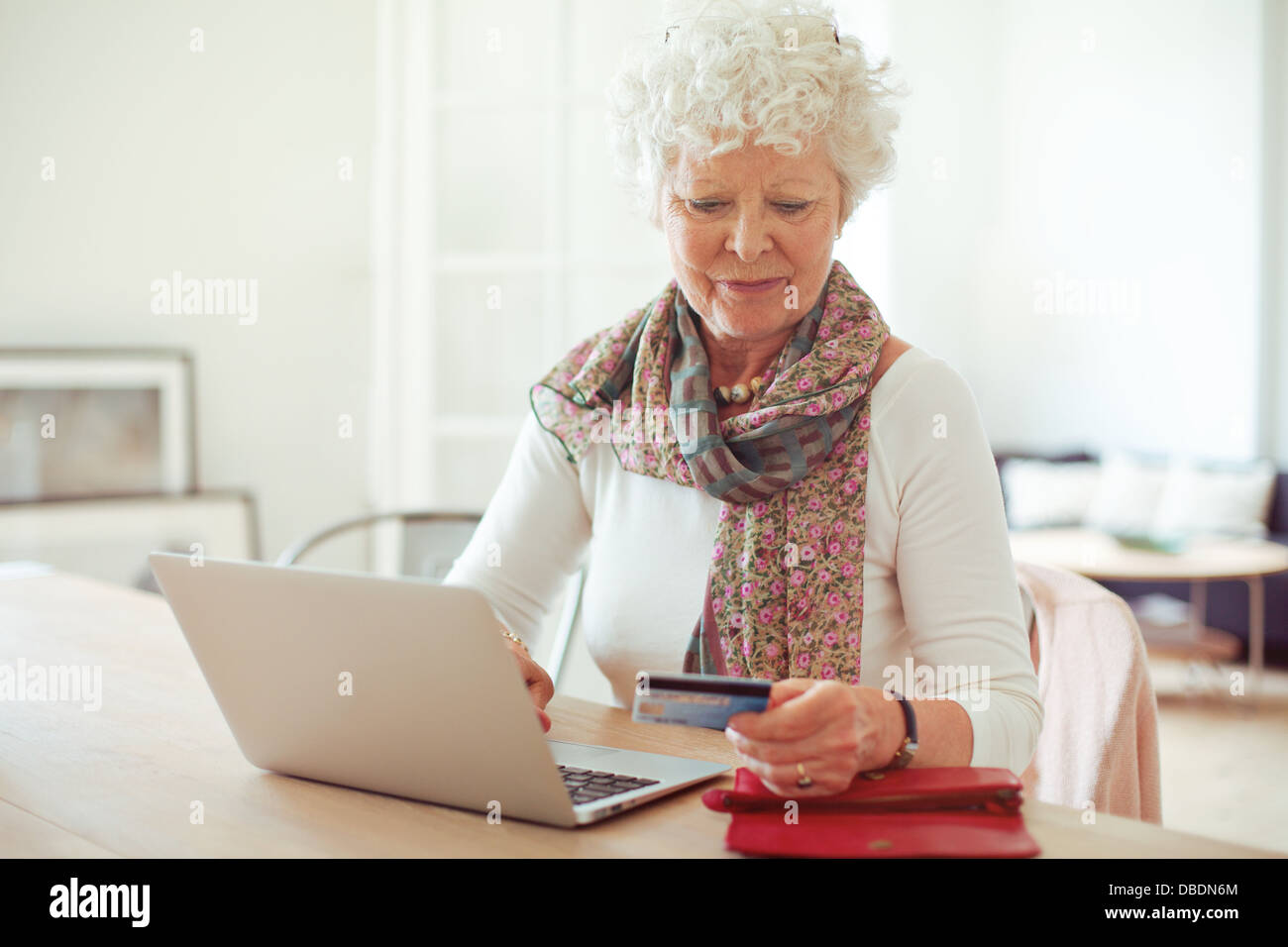 Grand-mère à l'avant du coffre de payer en ligne en utilisant une carte de crédit Banque D'Images