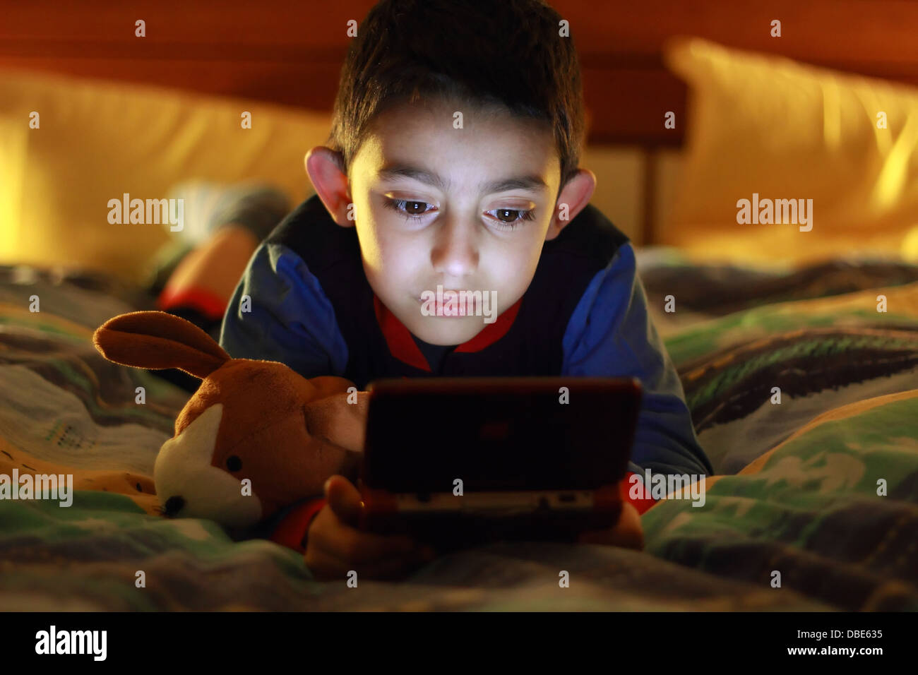 Kid au lit avec la console de jeux vidéo Banque D'Images