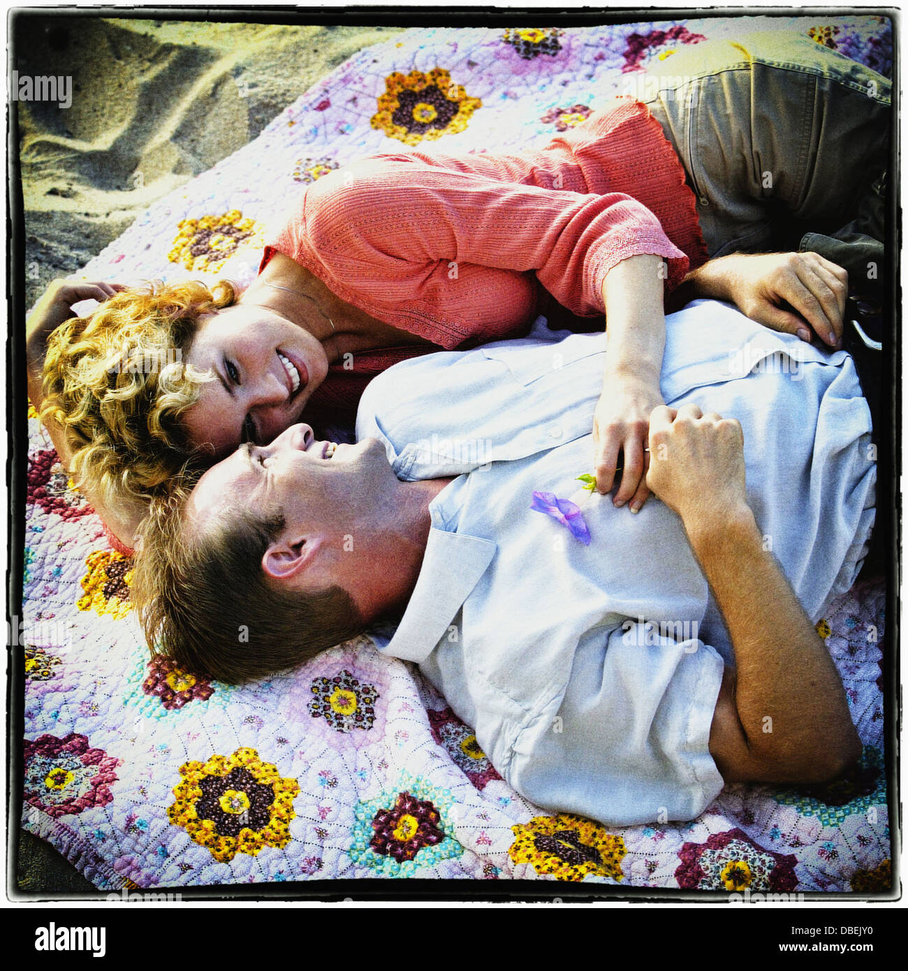 Smiling couple laying on beach blanket - Image de stock capturée avec un smartphone