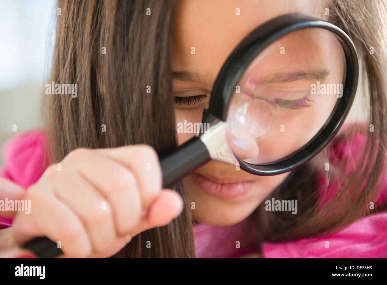 Fille hispanique à l'aide de loupe Banque D'Images