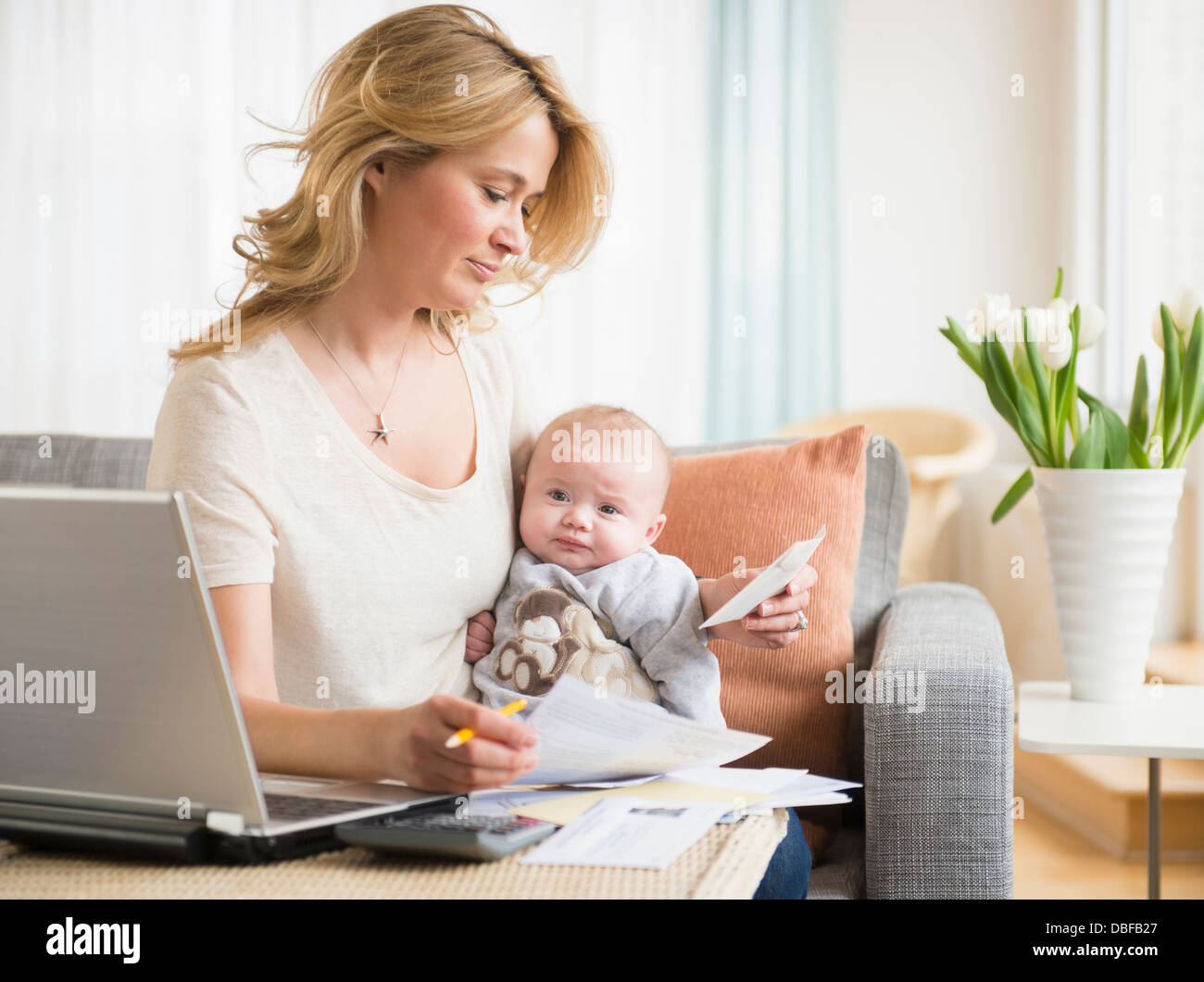 Caucasian mother with baby paying bills Banque D'Images