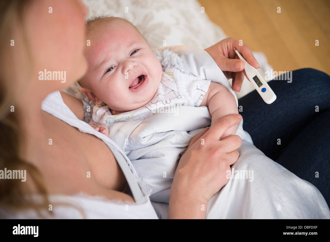Mère de race blanche prendre la température du bébé qui pleure Banque D'Images