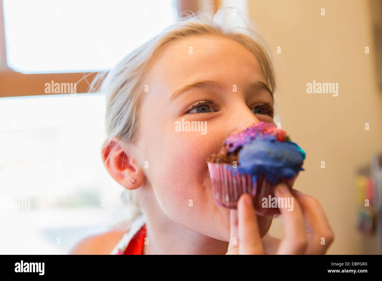 Caucasian girl eating cupcake Banque D'Images