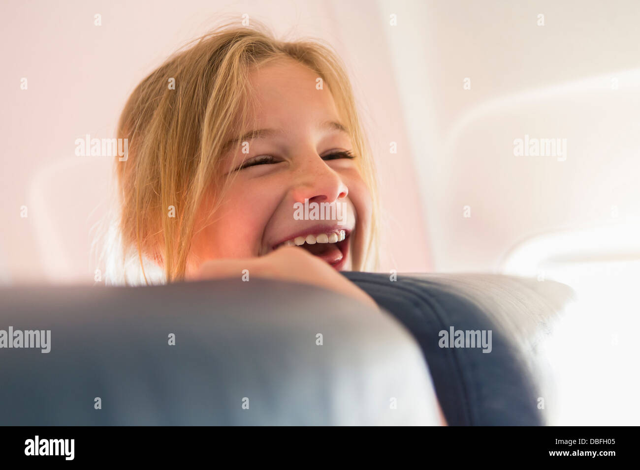 Caucasian girl laughing on airplane Banque D'Images