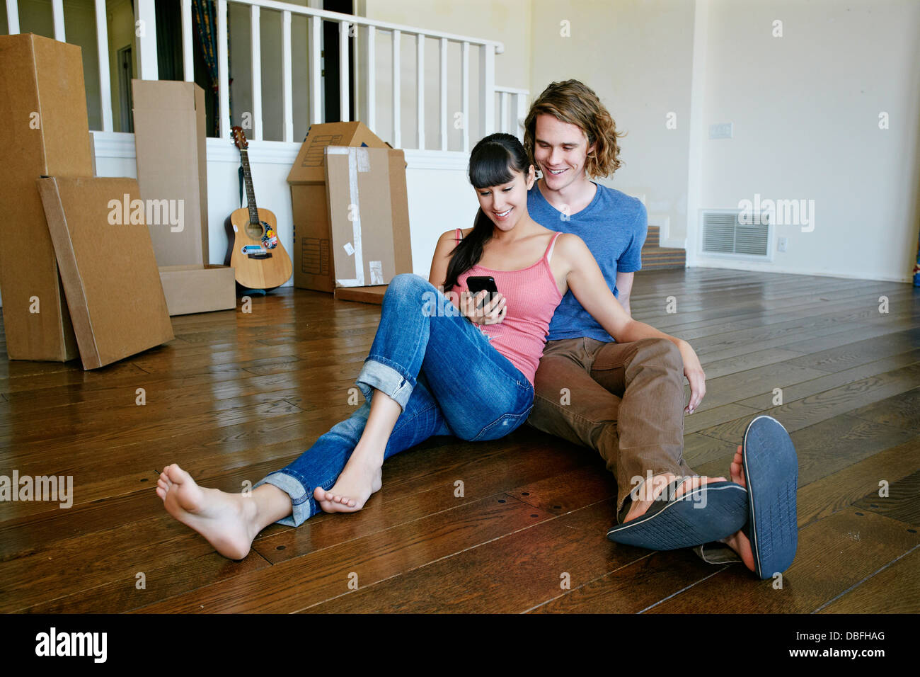 Couple using cell phone in new home Banque D'Images