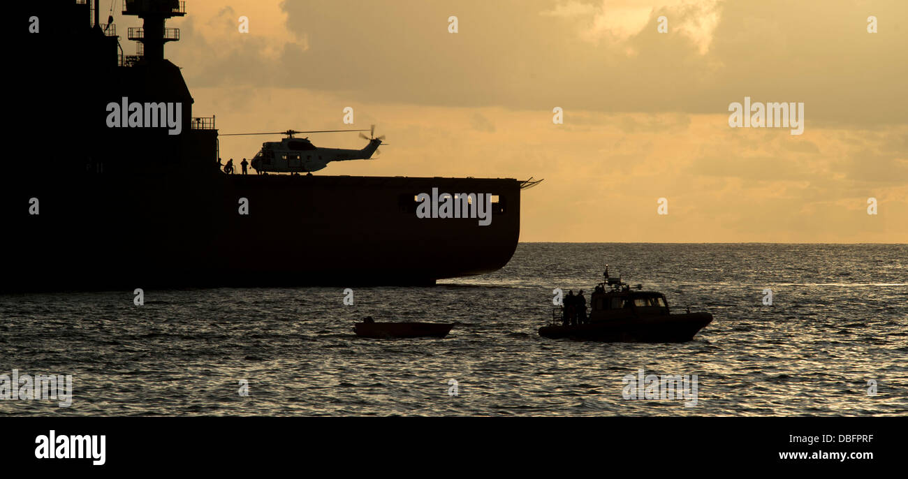 Un canot pneumatique à coque rigide (RHIB) à partir de la station d'amphibie Navire de débarquement USS Pearl Harbor (LSD 52) Remorque une l'équipage du bateau de pêche, fait à partir de la mer à bord de la commande de transport maritime de marchandises militaires et munitions ship USNS Matthew Perry (T-AKO-9), à l'autre o Banque D'Images