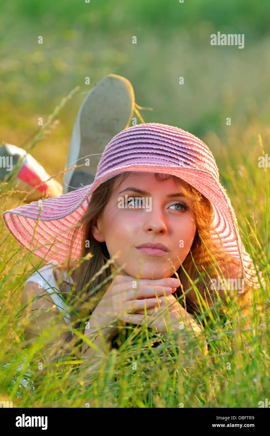 Teen girl lying in meadow grass dans l'heure d'été Banque D'Images