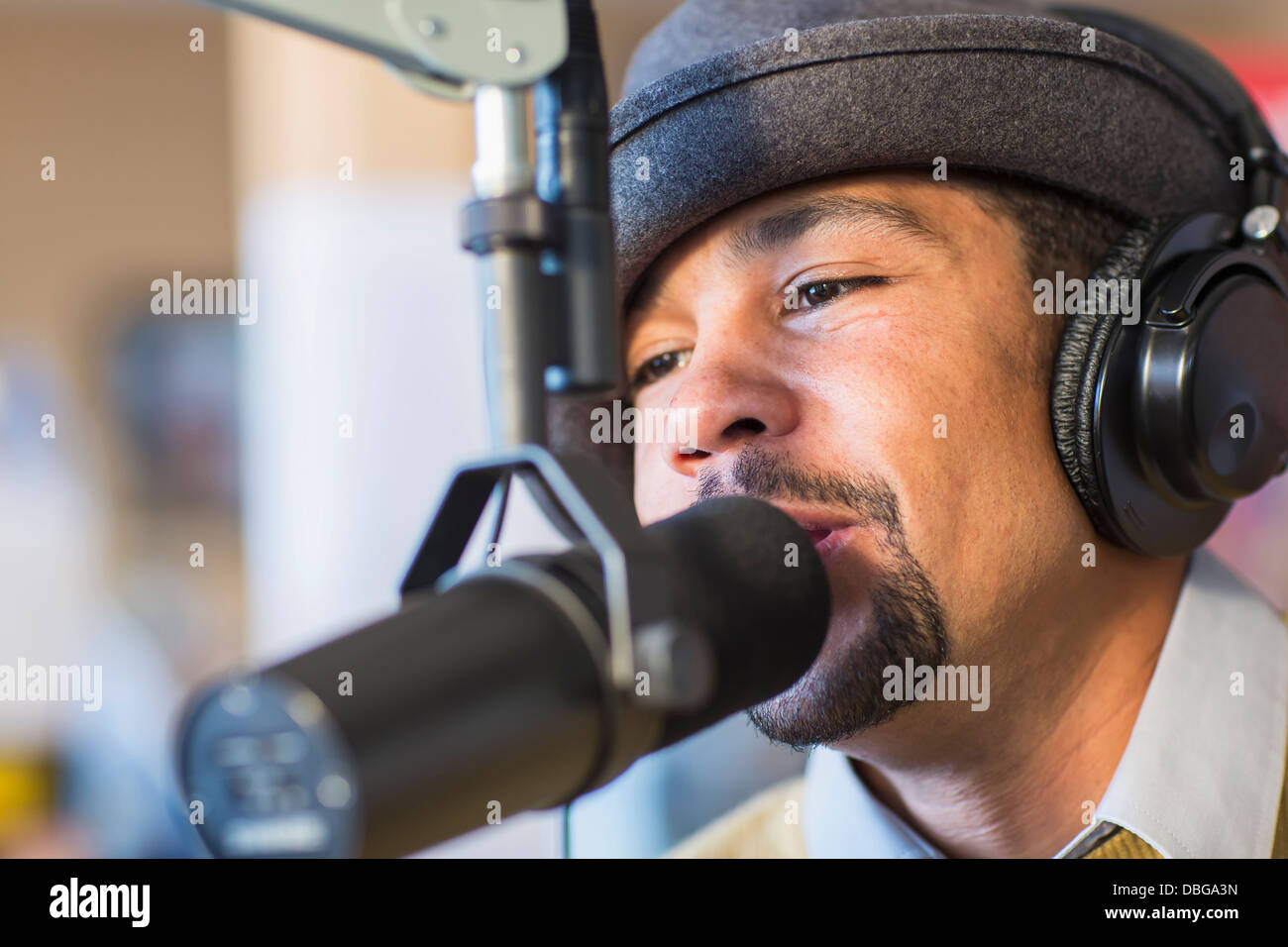 Mixed Race disc jockey parlant dans le micro de studio Banque D'Images