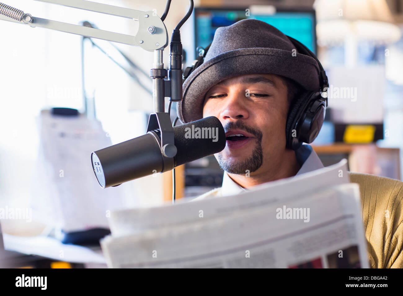 Mixed Race disc jockey parlant dans le micro de studio Banque D'Images